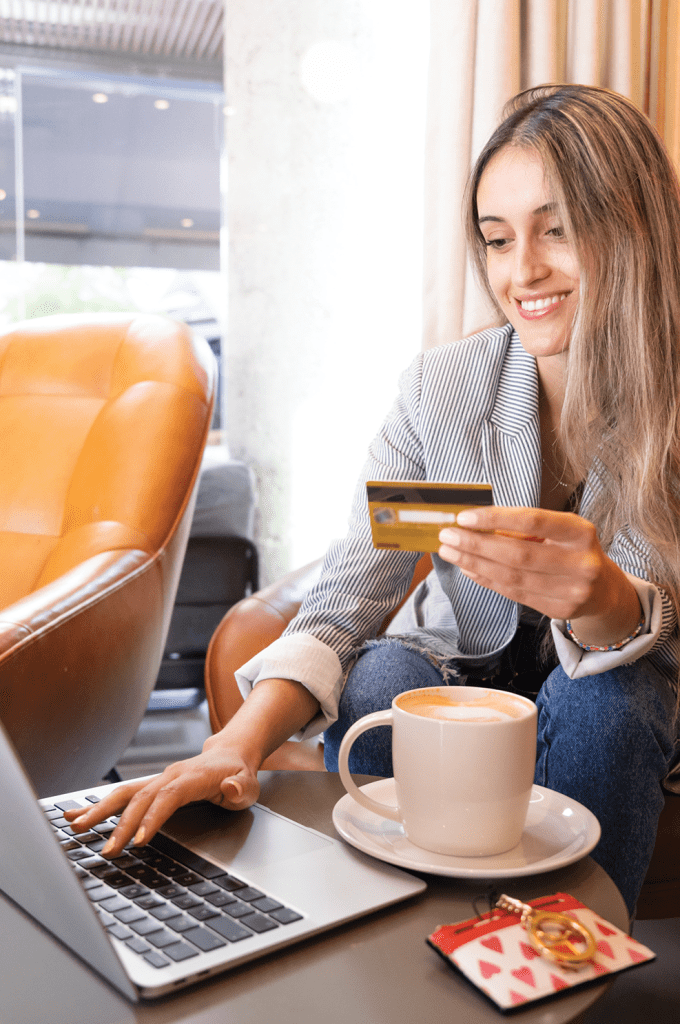 Woman sitting in a coffee shop making a purchase on her credit card using a merchant platform. 