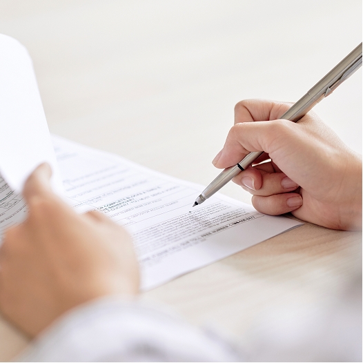 Close-up of a person's hands signing documents