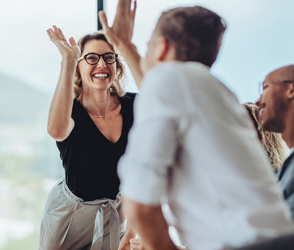 Two colleagues high-fiving across a table
