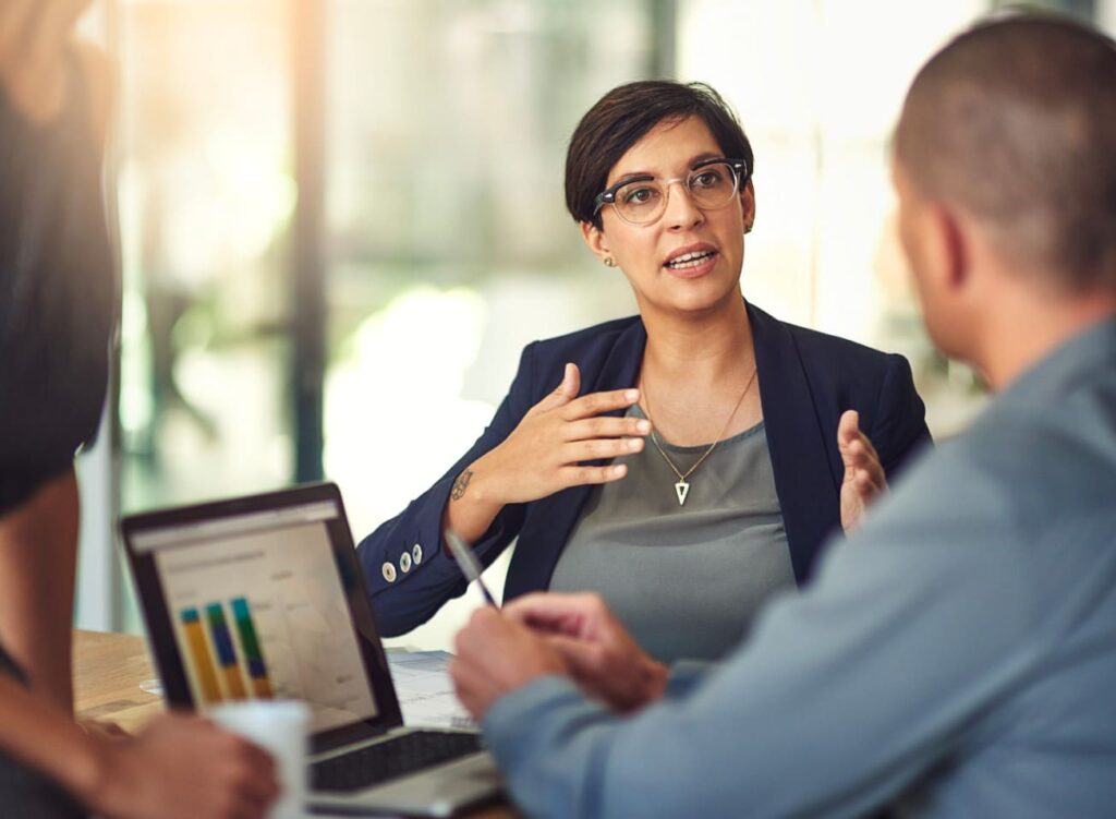 Business woman discussing chart on a laptop with colleague