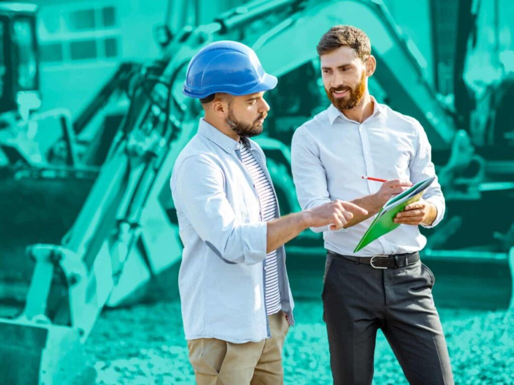 A construction foreman and business man looking at papers in front of machinery