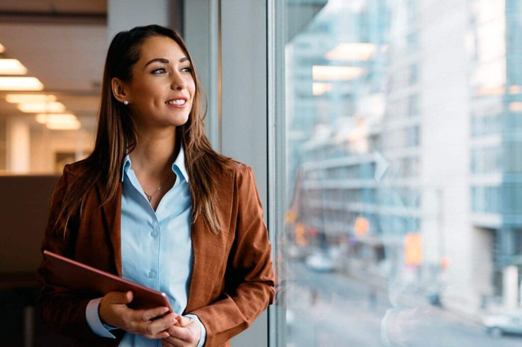 Woman holding laptop and looking out window